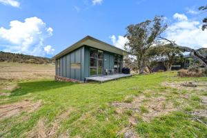 a small green house on a field with a grass yard at Ecocrackenback 19 Sustainable chalet close to the slopes in Crackenback