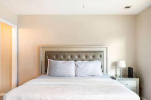 - une chambre dotée d'un grand lit avec des draps et des oreillers blancs dans l'établissement Discounted Gorgeous 2 bed/ 2.5 bathroom Townhome, à Riverdale