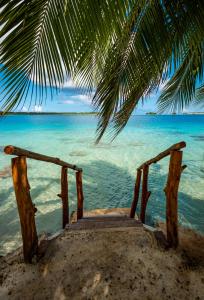a wooden stairway to the beach under a palm tree at Waterfront paradise 2 br; stunning sunsets in Bora Bora