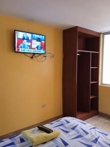 a bedroom with a bed and a tv on the wall at Hotel Residencial Miraflores in Loja