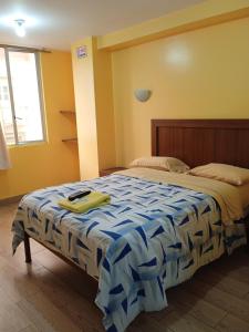 a bedroom with a bed with a blue and white comforter at Hotel Residencial Miraflores in Loja