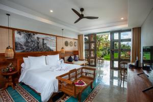 a bedroom with a white bed and a living room at Arya Arkananta Resort & Spa in Ubud