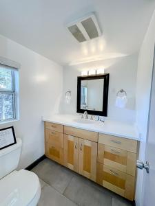 La salle de bains est pourvue de toilettes, d'un lavabo et d'un miroir. dans l'établissement Pristine 1BD/1BA Bungalow + Hot Tub - Ocean Park, à Los Angeles