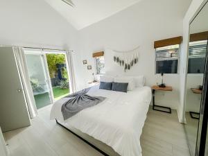 a white bedroom with a large bed and a window at Pristine 1BD/1BA Bungalow + Hot Tub - Ocean Park in Los Angeles
