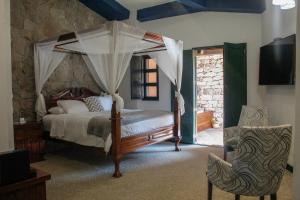 Un dormitorio con una cama con dosel y una silla. en Hotel Canaria, en Santeagueda