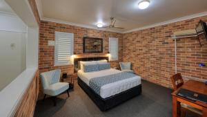 a bedroom with a bed and a brick wall at Heritage River Motor Inn in Grafton