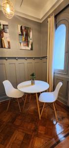 a table and two white chairs in a room at Hotel Voila Londres in Santiago