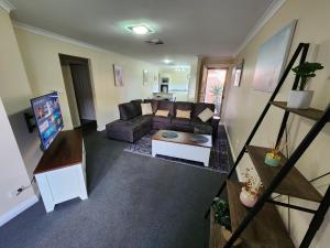 ein Wohnzimmer mit einem Sofa und einem Tisch in der Unterkunft Comfortable Villa across the road from the Historic Recreation Hotel in Kalgoorlie