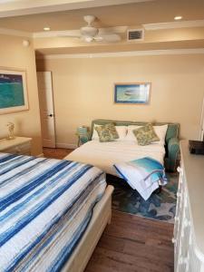 a bedroom with two beds and a ceiling fan at Bahamian Cottage - Heated Pool Walk to the Beach in Cocoa Beach