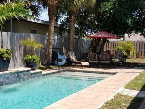 una piscina en un patio con mesa y sillas en Bahamian Cottage - Heated Pool Walk to the Beach en Cocoa Beach