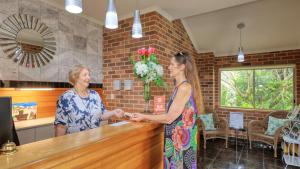 two women are shaking hands at a counter at Heritage River Motor Inn in Grafton