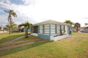 a small blue and white house with a palm tree at Downtown Cottage - Walk to the Beach & Restaurants in Cocoa Beach