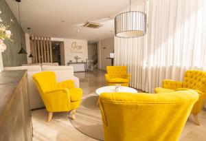 - une salle d'attente avec des chaises jaunes et une table dans l'établissement Gce Hoteles, à Cártama