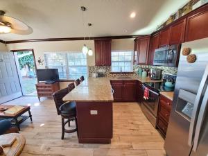 a kitchen with wooden cabinets and a large counter top at Hawaiian Cottage - Heated Pool Walk to the Beach in Cocoa Beach