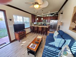 a living room with a blue couch and a kitchen at Hawaiian Cottage - Heated Pool Walk to the Beach in Cocoa Beach