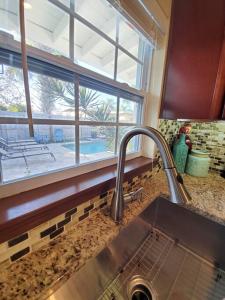 a kitchen with a sink and a window with a view of a pool at Hawaiian Cottage - Heated Pool Walk to the Beach in Cocoa Beach