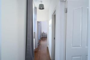 un pasillo con paredes blancas y suelo de madera dura en The Lodge - Newly Refurbished Suite with Dedicated Office Space, en Weybridge