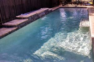 a swimming pool with blue water and steps in it at Tahitian Cottage - Heated Pool Walk to the Beach in Cocoa Beach