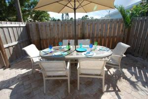 un tavolo con sedie e un ombrellone in un patio di Tahitian Cottage - Heated Pool Walk to the Beach a Cocoa Beach