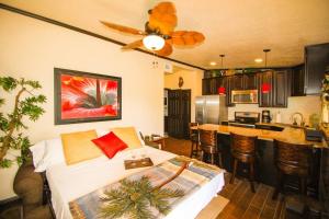 a bedroom with a bed and a kitchen with a ceiling fan at Tahitian Cottage - Heated Pool Walk to the Beach in Cocoa Beach