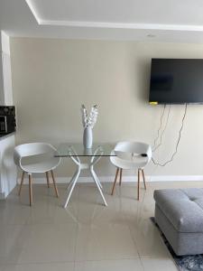 a living room with a glass table and two chairs at Large Luxurious Beach Front 1 Bedroom at Bayfront Villa in Portmore