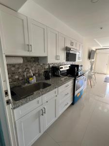 - une cuisine avec des placards blancs et un évier dans l'établissement Large Luxurious Beach Front 1 Bedroom at Bayfront Villa, à Portmore