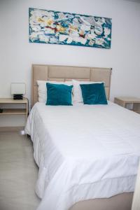 1 dormitorio con cama blanca y almohadas azules en Comfort Rooms Barranquilla Zafiro Deux, en Barranquilla