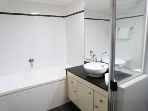a white bathroom with a sink and a bath tub at Ultra Convenient Apartment HER09029 in Sydney