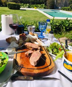 uma mesa com uma tábua de cortar com carne e salada em Los trinos em Coronel Suárez