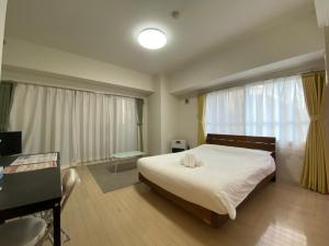 a bedroom with a bed and a desk and window at Downtown area Spacious cozy room Susukino IK301 in Sapporo
