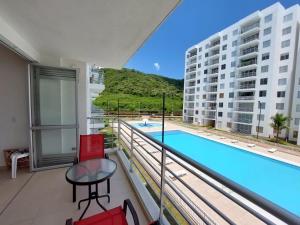 un balcón con piscina y sillas rojas en Aqualina Orange Apartamento Piso 3 Vista a Piscina 3 Habitaciones, en Girardot