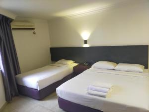 two beds in a hotel room with towels on them at Seremban Inn in Seremban