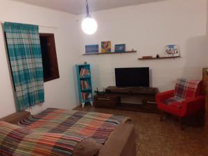 a living room with a bed and a tv at Casa das Violetas - Serra do Cipó in Serra do Cipo