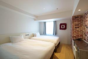 2 camas en una habitación con una pared de ladrillo en Shibuya Hotel En, en Tokio