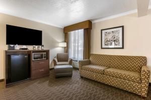 Best Western Airport Albuquerque InnSuites Hotel & Suites في ألباكيركي: غرفة معيشة مع أريكة وتلفزيون بشاشة مسطحة