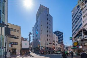 a tall building on a city street with buildings at Shibuya Hotel En in Tokyo