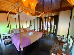 ein Schlafzimmer mit einem Himmelbett in einem Zimmer mit Fenstern in der Unterkunft LA A NATU Pranburi in Sam Roi Yot
