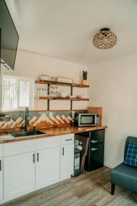 La cuisine est équipée de placards blancs, d'un évier et d'un four micro-ondes. dans l'établissement Triple Nickel Pines Cabins, à Grants Pass