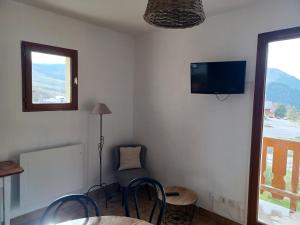 a room with a table and chairs and a tv on the wall at Studio Albiez-Montrond, 1 pièce, 4 personnes - FR-1-618-22 in Albiez-Montrond