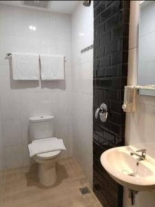 a white bathroom with a toilet and a sink at Odua Golden Mansyur Medan in Medan