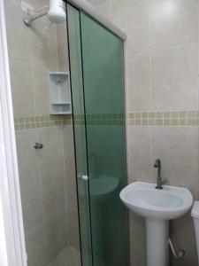 Un baño con lavabo y ducha de cristal. en Kitnet Asturias 51B no Ed. Guariatã, próximo a praia das Astúrias em Guarujá, en Guarujá