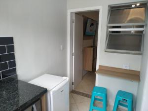 una cocina con dos taburetes azules frente a un mostrador en Kitnet Asturias 51B no Ed. Guariatã, próximo a praia das Astúrias em Guarujá, en Guarujá