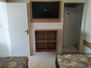 Una habitación con un televisor en la pared y una cama. en Kitnet Asturias 51B no Ed. Guariatã, próximo a praia das Astúrias em Guarujá, en Guarujá