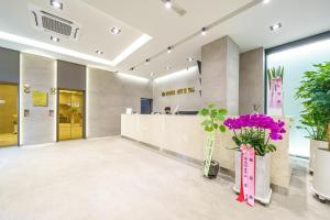 a lobby with a counter with purple flowers in vases at Browndot Hotel Sangmu in Gwangju