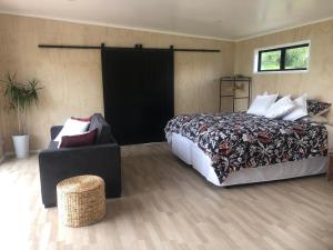 um quarto com uma cama grande e uma cadeira em Whakaipo Bay Cabin Retreat Taupo em Taupo
