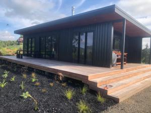 a small house with a wooden deck in a field at Whakaipo Bay Cabin Retreat Taupo in Taupo