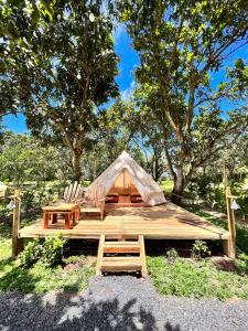 a tent on a wooden deck with two chairs and trees at Binifarm Tropical Retreat in Cu Chi