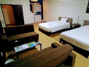 うるま市にあるホワイトビーチイン石川のベッド2台とソファが備わるホテルルームです。
