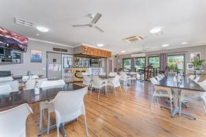 a dining room with tables and white chairs at BIG4 Lake Maraboon Holiday Village in Gindie