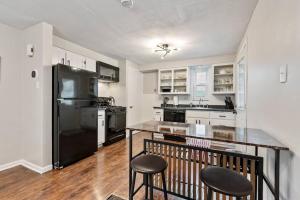 a kitchen with a black refrigerator and two bar stools at Spacious Home, 15min from Downtown, Private Garage & Patio in Pittsburgh